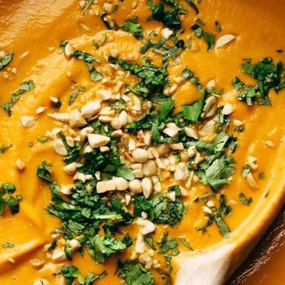 Spicy Carrot Soup in pot with wooden spoon.