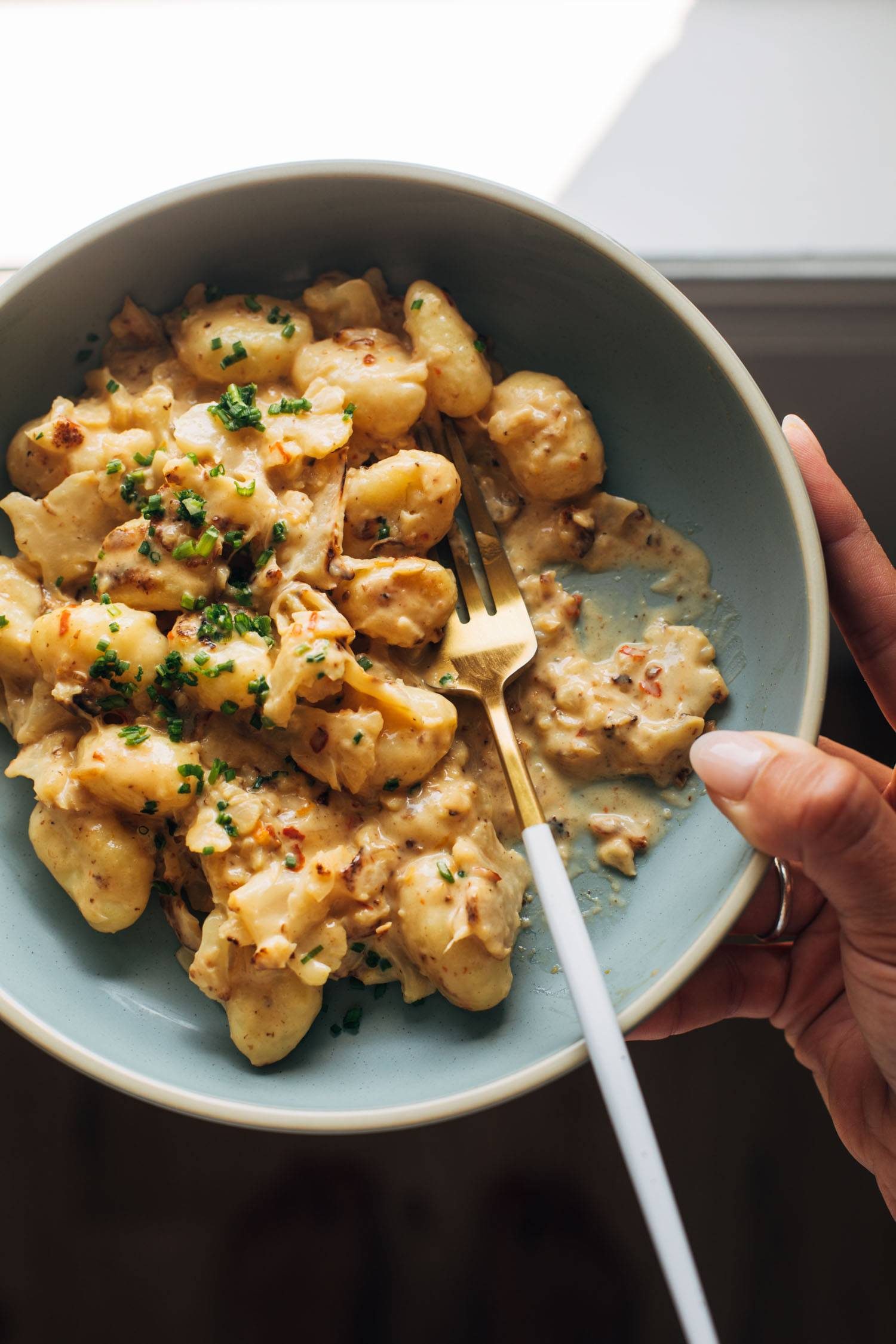 Gnocchi in a bowl with cauliflower, orange, and a creamy sauce.