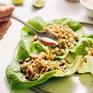 Chicken lettuce cups on plate with hand and fork going in for a bite.