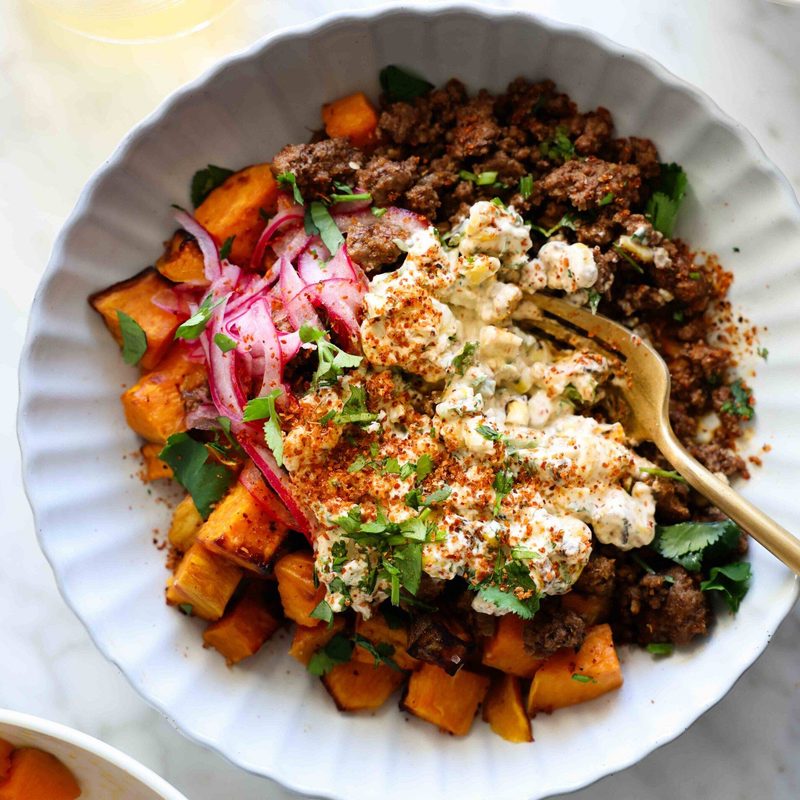 Beef and sweet potato in a bowl with street corn.