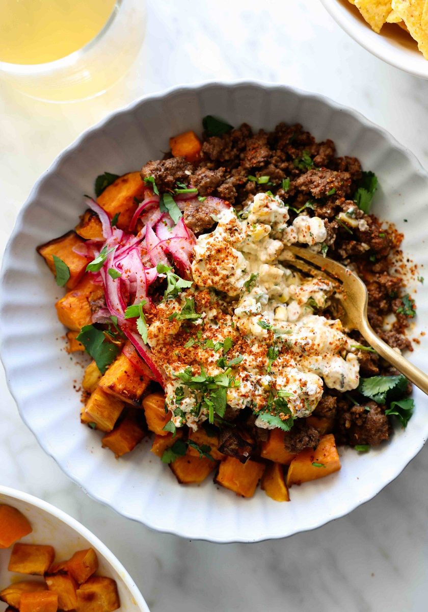 Beef and sweet potato in a bowl with street corn.