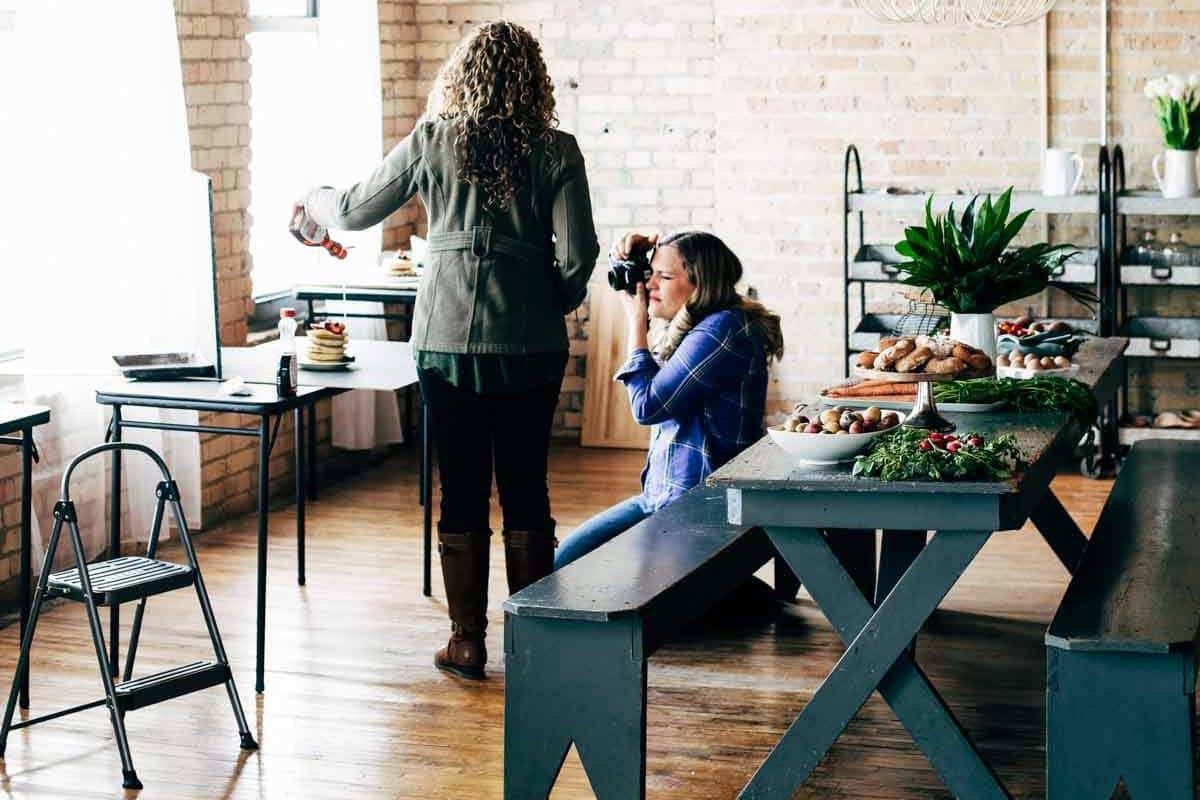 Women taking photos of syrup on pancakes.